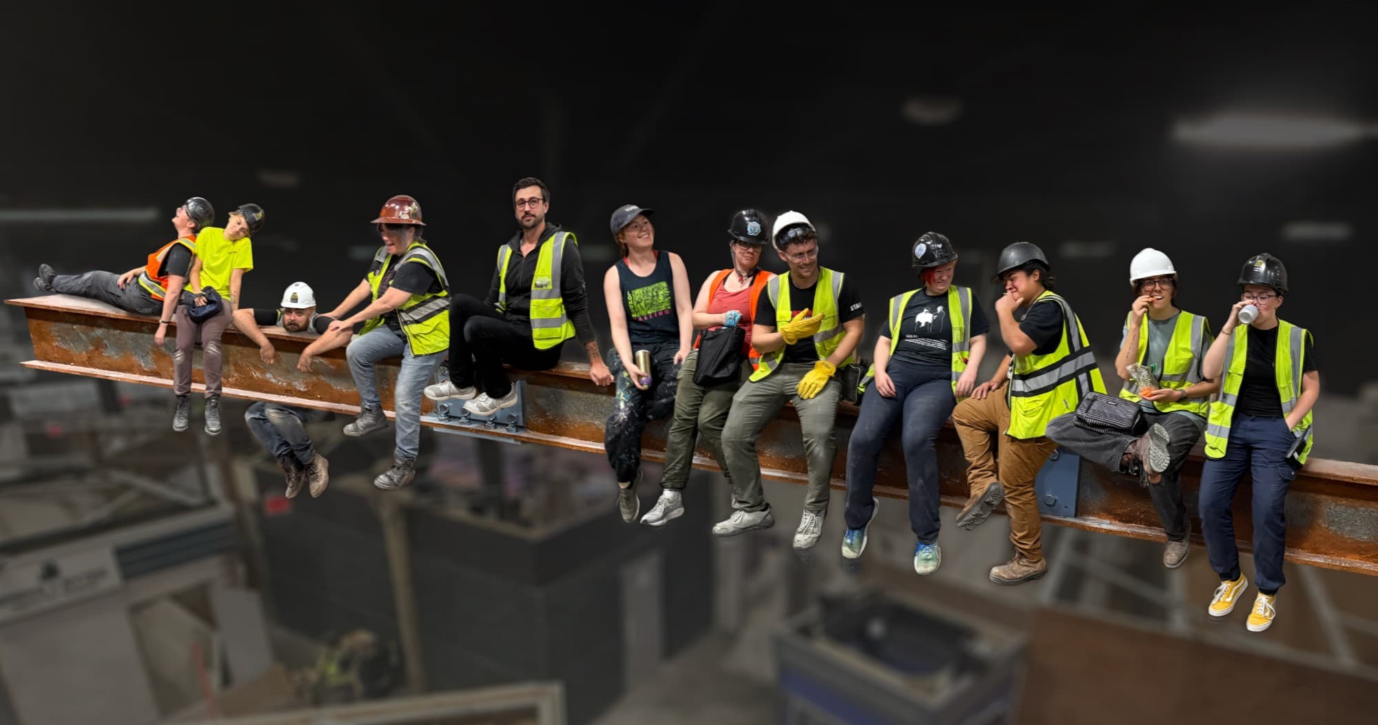 The team in hard hats and hi-vis vests sitting in a row along a steel beam